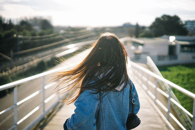 Rear view of woman standing on footbridge