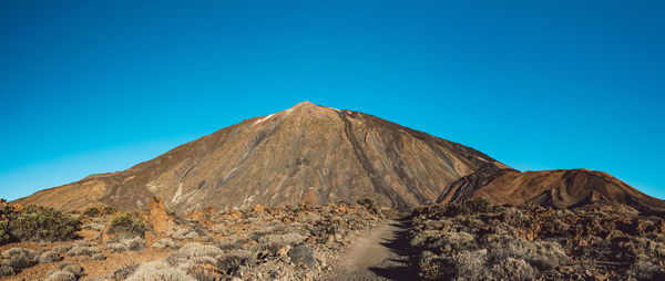 Scenic view of volcanic mountain against clear blue sky