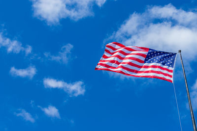 Low angle view of american flag waving against blue sky