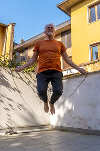 Full length of man skipping against built structure