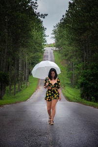 Full length of woman standing on road in rain