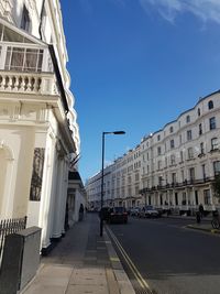 Road amidst buildings in city against sky