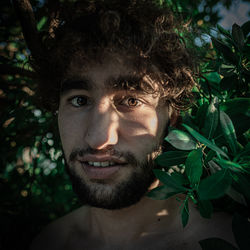 Portrait of young smiling man standing by plants