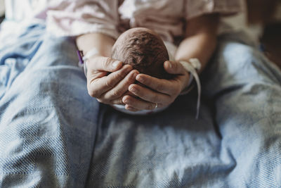 Macro view of mothers hands holding newborn boy's head