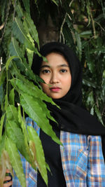 Portrait of beautiful young woman standing by leaves