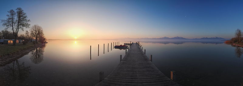 Pier over lake against sky during sunset