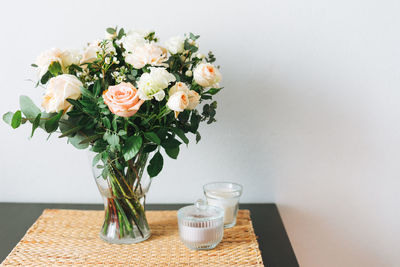 Bouquet of white and pink roses, greens and other flowers on table on the kitchen, home decor