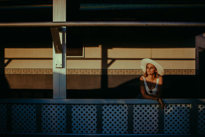 Woman looking away while sitting on railing