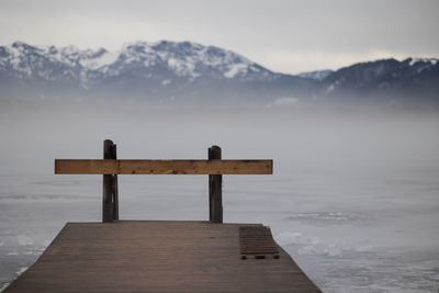 Wooden pier on snowcapped mountains against sky