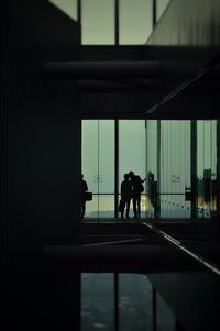 Silhouette couple standing against glass wall at airport