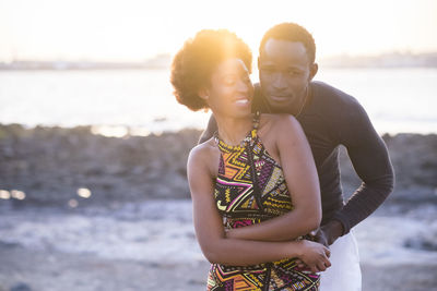 Portrait of young woman standing with girlfriend at beach