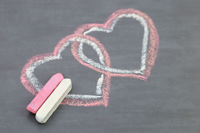 Close-up of chalks by heart shape drawn on table