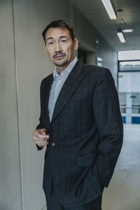 Businessman with hands in pockets standing at laboratory corridor