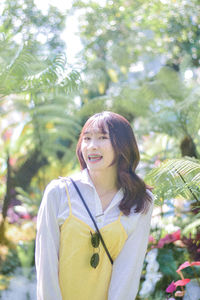 Portrait of young woman standing against plants