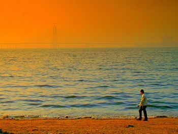 Man standing on beach against sky during sunset