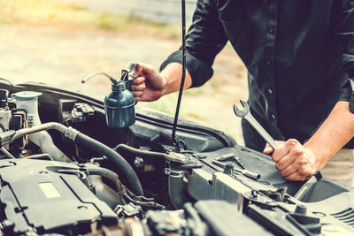 Midsection of man working on motorcycle