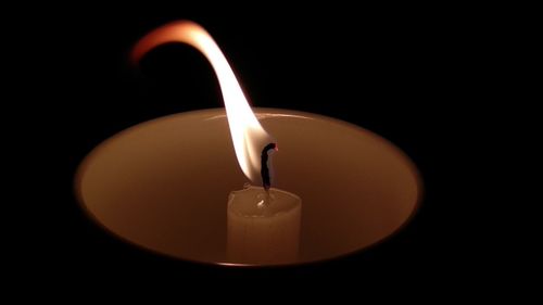 Close-up of lit candle against black background