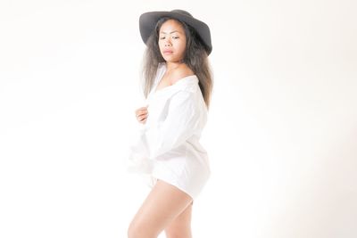 Young woman wearing hat standing against white background
