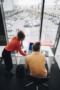 High angle view of multi-ethnic colleagues using laptop at desk in office