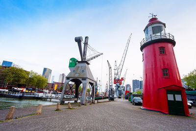 Lighthouse amidst buildings in city against sky