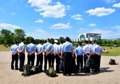 Rear view of soldiers wearing uniforms standing against sky