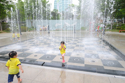 Full length of boy standing on wet walkway in city