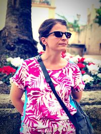 Mid adult woman wearing sunglasses standing against plants