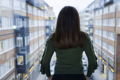 Woman looking through window at residential buildings