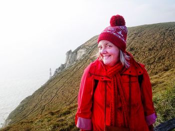 Portrait of smiling mature woman standing on mountain against sky during winter