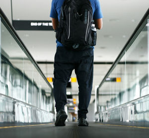 Low section of man walking on escalator