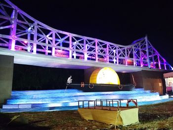 Illuminated bridge over river against sky at night