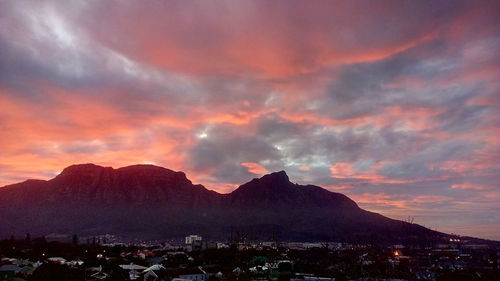Townscape by mountains against romantic sky at sunset