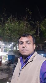 Portrait of young man standing in city at night