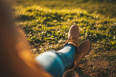 Low section of woman wearing shoes relaxing on field