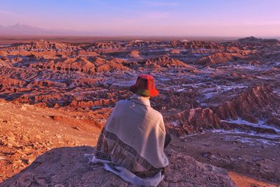 Rear view of man on rock against sky