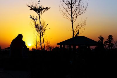 Silhouette built structure against orange sky