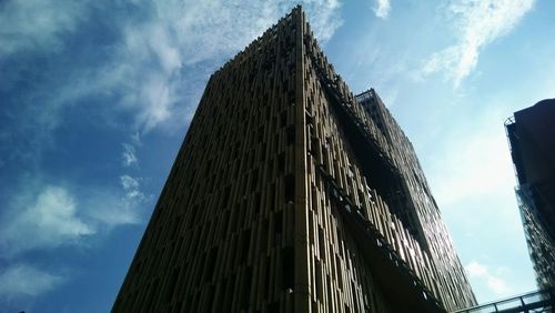 Low angle view of skyscrapers against cloudy sky