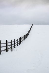 Old wooden fence in a winter rural landscape with dark clouds and snow, paltinis area, sibiu county,