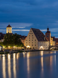 Illuminated buildings by mosque against sky