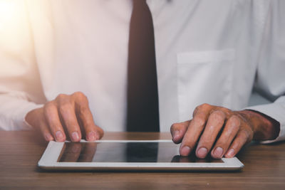 Close-up of man using smart phone on table