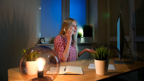 Woman looking at camera while sitting on table at home