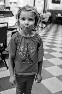 Portrait of cute girl making a face while standing on tiled floor