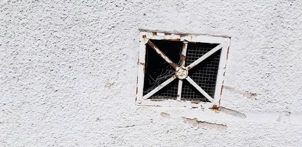 Close-up of broken window on building wall