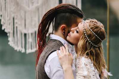 Two happy people in love the bride and groom in wedding outfits embrace by the lake and mountains