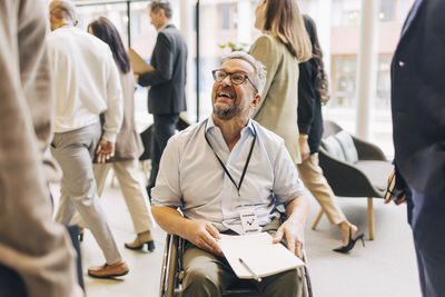 Smiling male entrepreneur with disability sitting on wheelchair during seminar at convention center