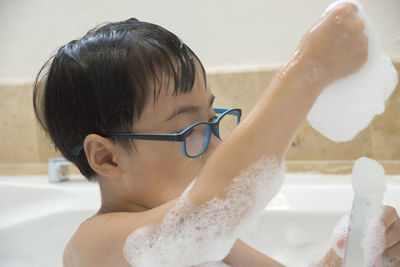 Shirtless boy bathing in bathtub at home