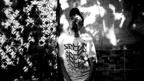 Portrait of young man standing against wall