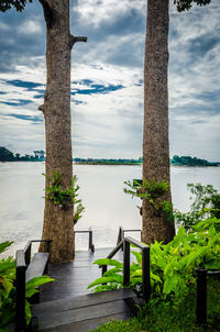 Wooden posts in lake against sky