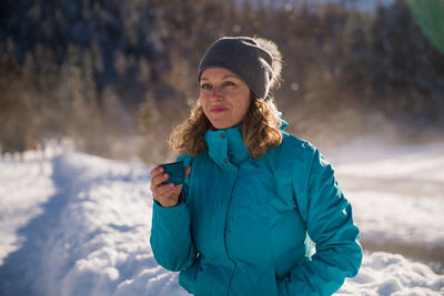 Young man using phone while standing on snow