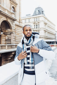 Young african man on street, snow winter season, city portrait